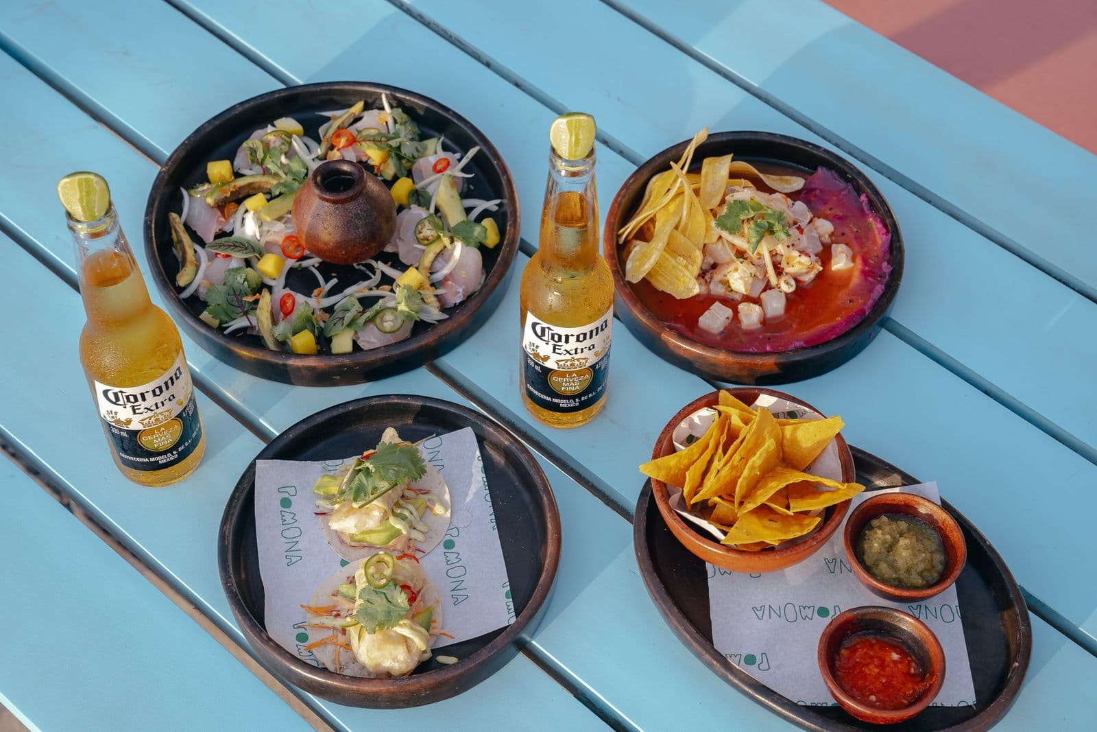 Ceviche, tacos and nachos with salsas on a blue table